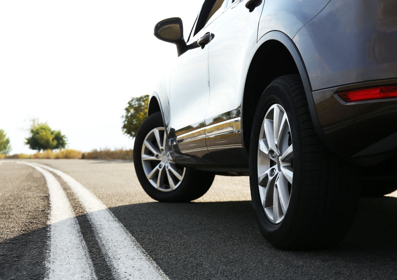 Side view of a 4 door SUV on the road covered by auto insurance