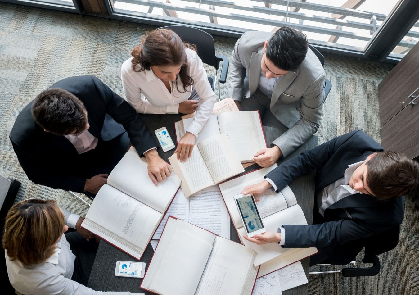 Business associates strategizing with digital and print resources