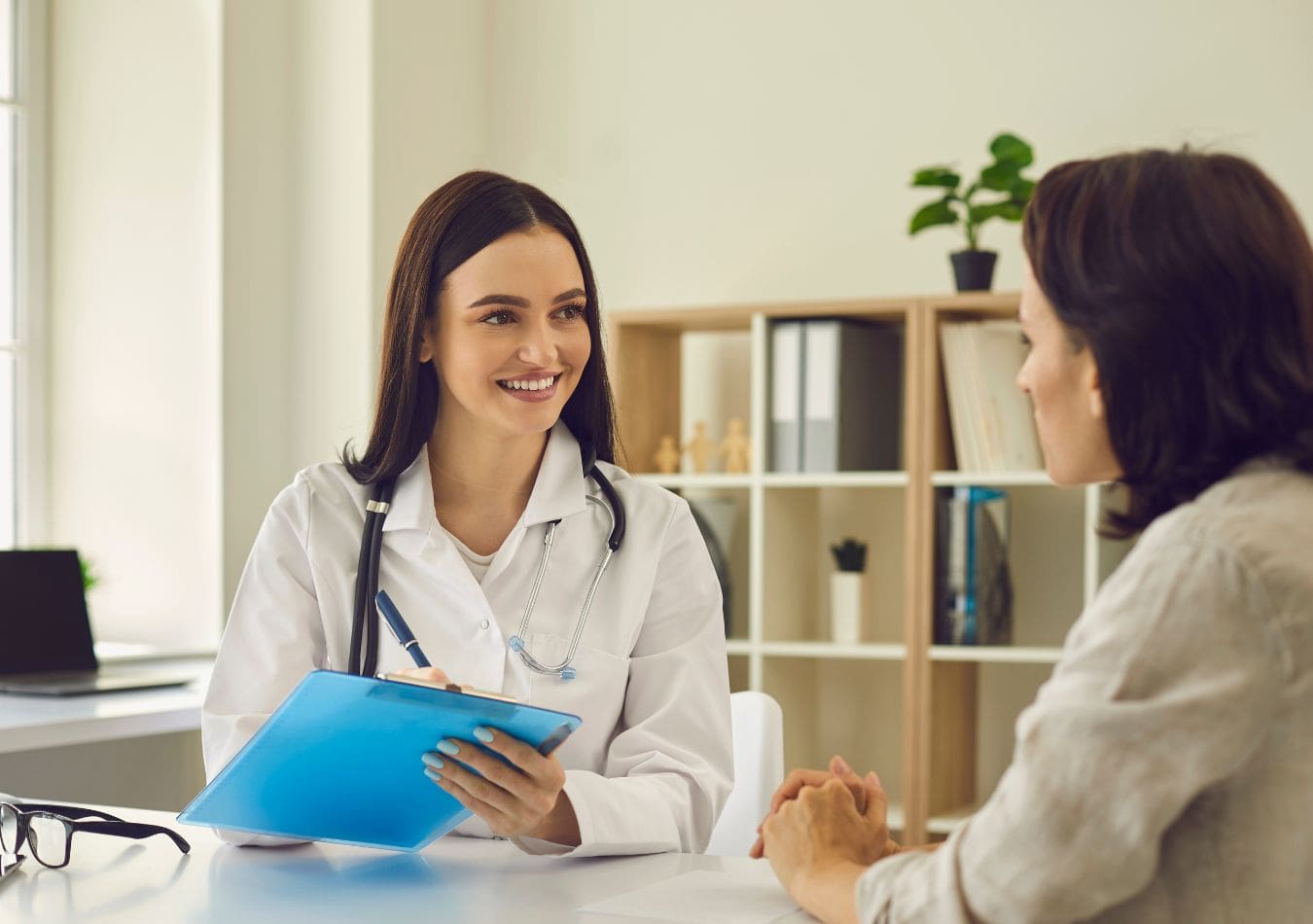 Female doctor talking with patient while filing out a clipboard health insurance form