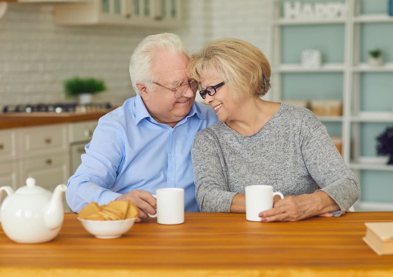 Married couple smiling while drinking coffee at the kitchen table